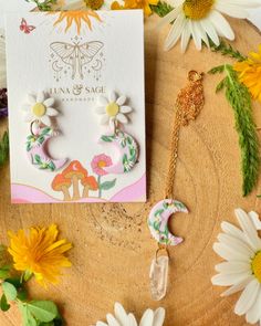 the earrings are on display next to flowers and a card with an insect in it