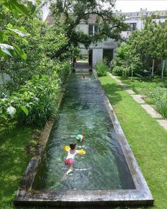 a person swimming in a small pool surrounded by greenery