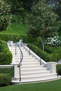 a set of white stairs leading up to a lush green hillside