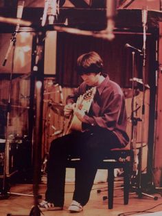 a man sitting in a chair playing an electric guitar