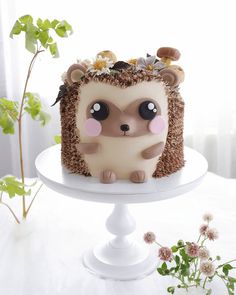 a hedgehog cake sitting on top of a white plate next to flowers and greenery