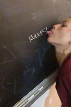 a woman writing on a blackboard with white chalk