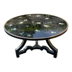 a table with water lilies on the top and black legs, against a white background