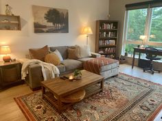 a living room filled with furniture and a large window covered in lots of natural light