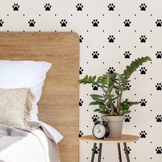 a bed with a wooden headboard next to a wall with black and white paw prints