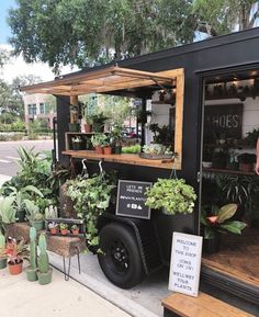 a man standing next to a black truck filled with potted plants and greenery