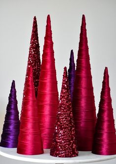 red and purple cones are sitting on a white shelf next to each other in the shape of trees