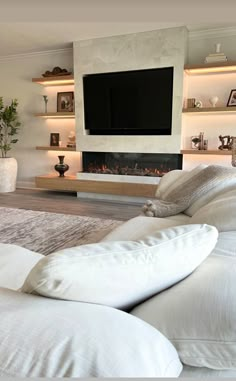 a living room with white couches and a flat screen tv mounted on the wall