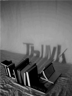 three books are sitting on a table with their shadows