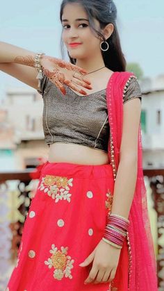 a woman in a red and gold lehenga with her hands on her hip