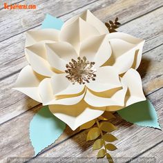 an origami flower on a wooden surface with leaves and flowers in the center