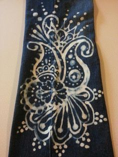 a blue tie with white designs on it hanging from a hook in a room next to a wall