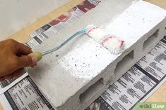 a person using a toothbrush to brush the cement on top of a newspaper page