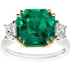 an emerald and diamond ring with three diamonds on the band, set in white gold