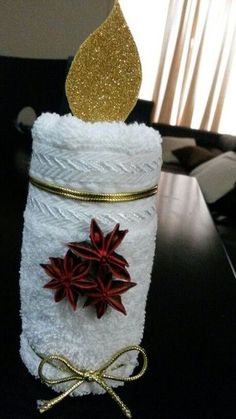 a towel wrapped in white paper with gold glitter on top and red poinsettia