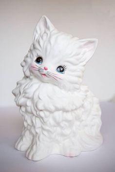 a white cat figurine sitting on top of a table