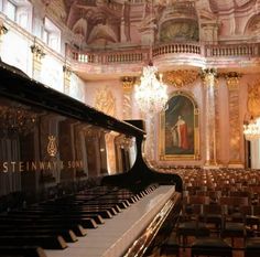 a grand piano in an ornate room with chandeliers