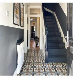 an entry way with black and white tile flooring next to a stair case in a home