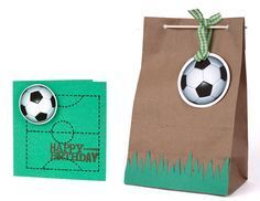 a brown paper bag with a soccer ball on it next to a green gift bag