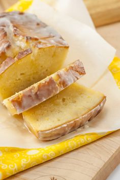 two slices of glazed pound cake sitting on top of a cutting board next to a yellow napkin