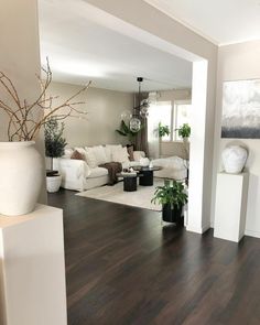 a living room filled with white furniture and potted plants on top of hard wood floors