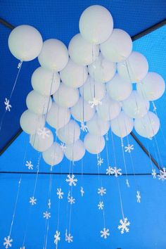 a bunch of white balloons floating on top of a laptop computer screen with snowflakes hanging from it