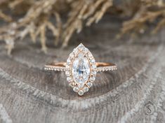 an engagement ring with a pear shaped diamond surrounded by smaller round diamonds on a piece of fabric