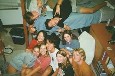 a group of young people sitting on top of a bed in a bedroom next to each other