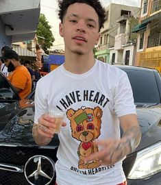 a young man holding a drink in front of a car