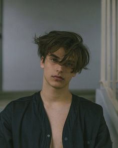 a young man with no shirt on standing in front of stairs and looking at the camera