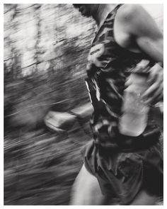 black and white photograph of a man running through the woods with trees in the background