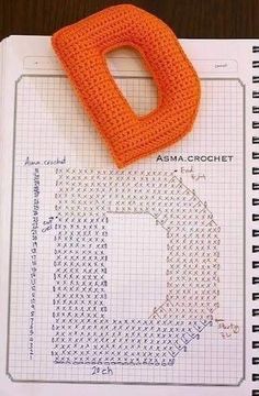 an orange crocheted object sitting on top of a piece of paper