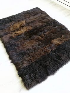 a brown and black area rug sitting on top of a white floor next to a radiator