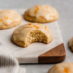 some cookies with icing and orange zest on them are sitting on a table