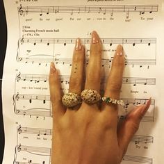 a woman's hand with two rings on top of sheet music