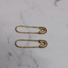 two gold paper clips sitting on top of a marble counter