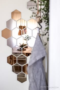 a mirror hanging from the side of a wall next to a table with a potted plant on it