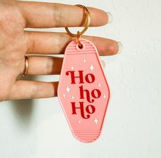 a hand holding a pink keychain with the word ho hoo on it