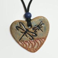 a heart shaped pendant with dragonflies on it's back and the words love written in