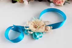 a blue ribbon with flowers and pearls on it