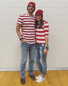 a man and woman standing next to each other in front of a white brick wall