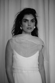 a woman in a white dress is posing for a black and white photo with her hands on her hips