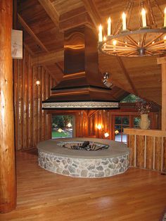 a fireplace in the middle of a room with wood paneling and chandelier