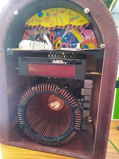 an old fashioned radio sitting on top of a wooden table in front of a colorful wall