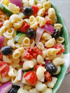 a green bowl filled with pasta salad on top of a table