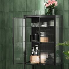 a shelf with some bottles and soaps on it in front of a green tiled wall