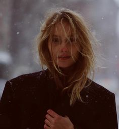 a woman standing in the snow with her hand on her chest