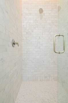 a walk in shower sitting next to a white tiled wall