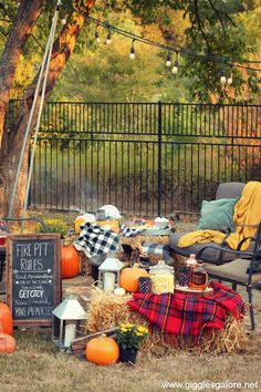 an outdoor area with pumpkins, hay and chairs