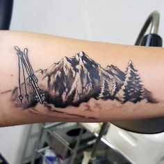 a man's arm with a mountain and skis tattoo on the left forearm